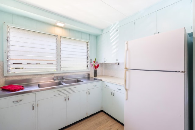 kitchen with backsplash, sink, light hardwood / wood-style flooring, white fridge, and white cabinetry