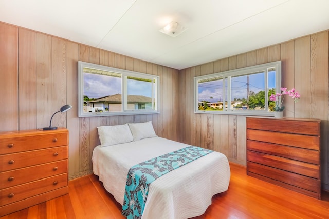 bedroom featuring wood walls and light hardwood / wood-style flooring