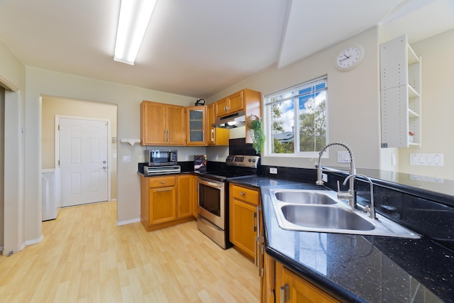 kitchen featuring stainless steel electric range oven, sink, dark stone counters, and light wood-type flooring