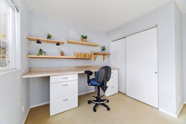 home office with built in desk and light colored carpet