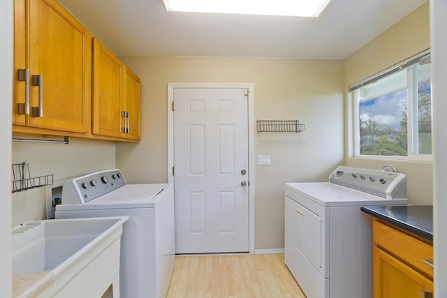 washroom with cabinets, separate washer and dryer, light hardwood / wood-style flooring, and sink