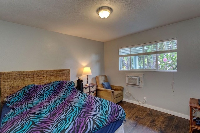 bedroom featuring a wall unit AC, a textured ceiling, and hardwood / wood-style flooring