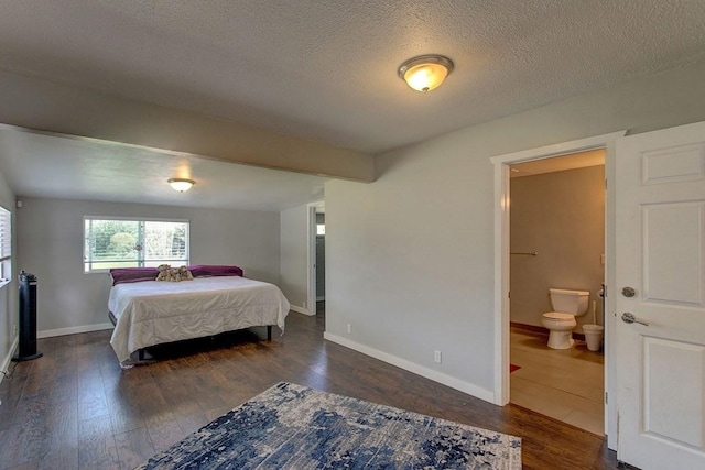 bedroom with ensuite bath, dark hardwood / wood-style flooring, and a textured ceiling