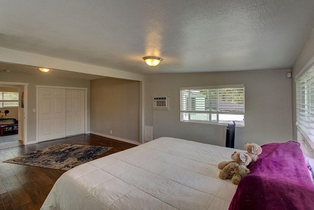 bedroom with a wall unit AC, multiple windows, a closet, and wood-type flooring