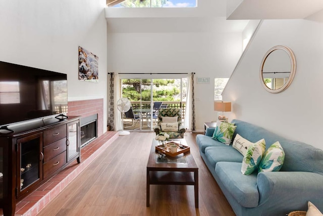 living room featuring a fireplace, a towering ceiling, and light hardwood / wood-style floors