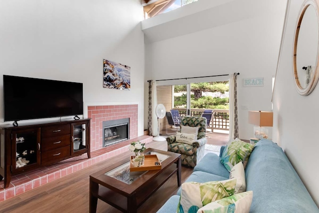 living room with wood-type flooring, a fireplace, and a high ceiling