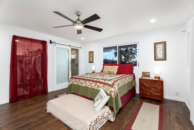 bedroom with ceiling fan, a barn door, and dark hardwood / wood-style flooring