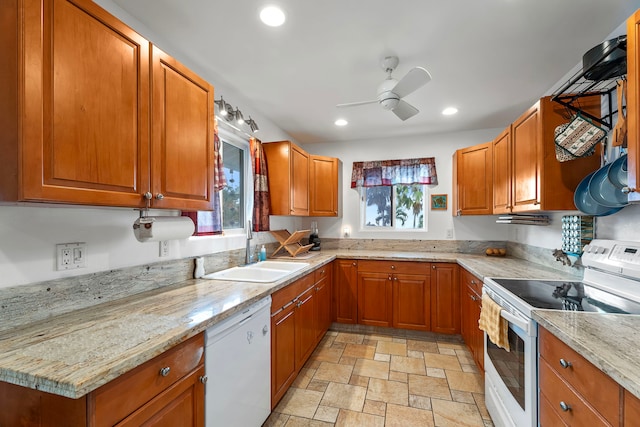 kitchen with white appliances, light stone counters, ceiling fan, and sink