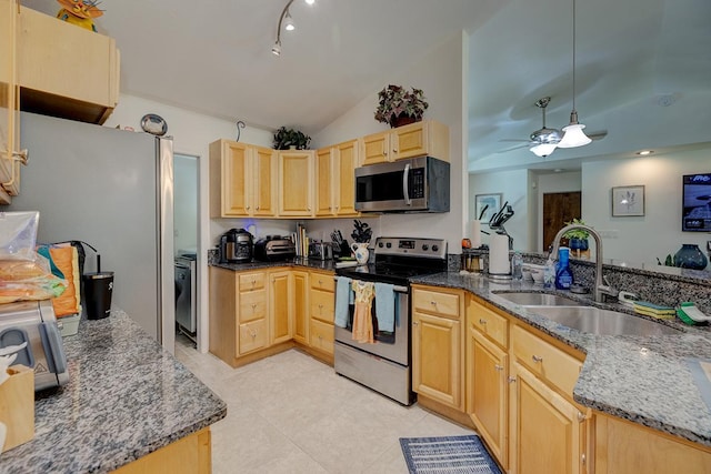 kitchen with appliances with stainless steel finishes, light brown cabinets, dark stone counters, and sink