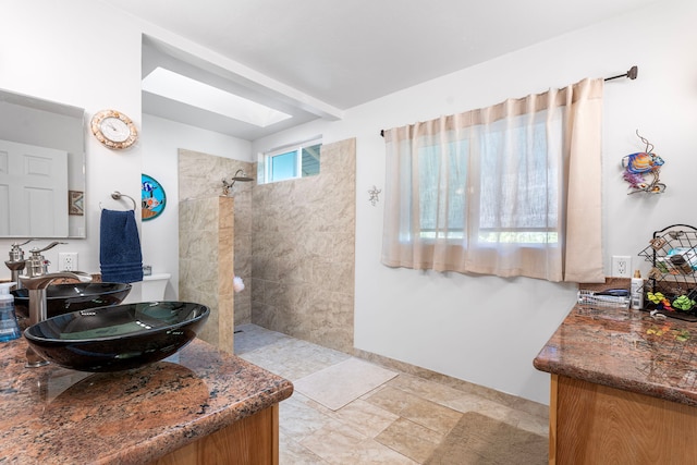 bathroom with a tile shower and vanity