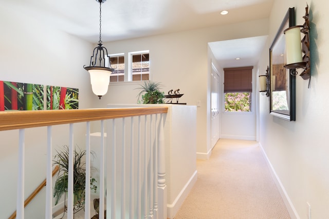 corridor with a healthy amount of sunlight and light colored carpet