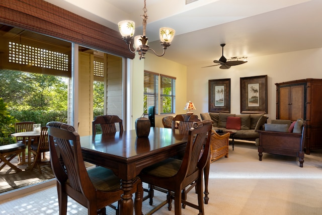 dining space with light carpet and ceiling fan with notable chandelier