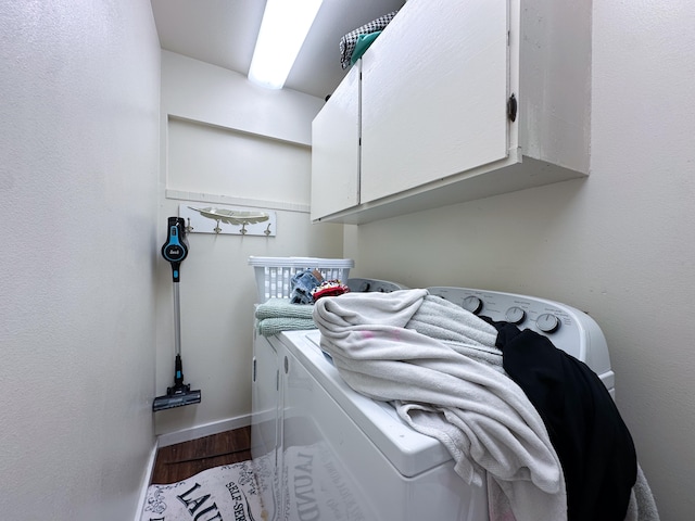 laundry room with hardwood / wood-style flooring, cabinets, and washing machine and dryer