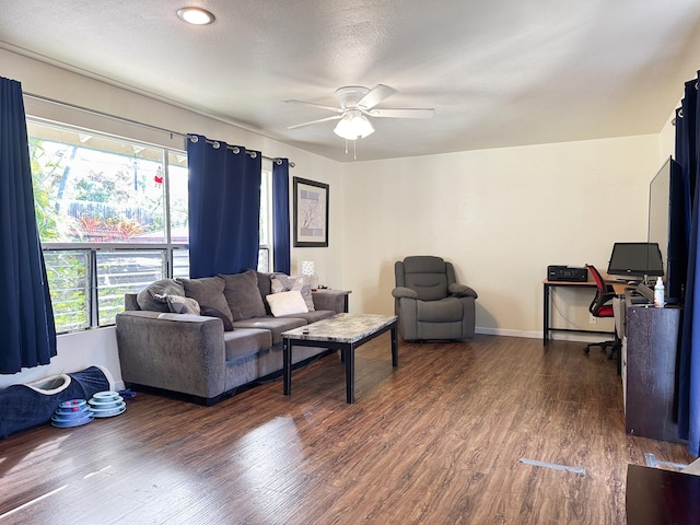 living room featuring ceiling fan, a textured ceiling, and dark hardwood / wood-style floors