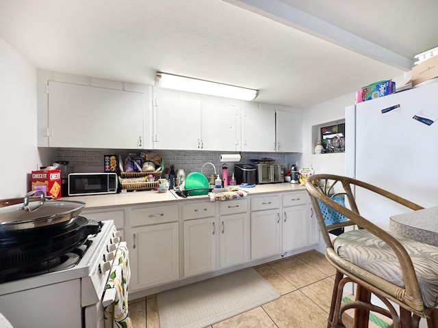 kitchen with white cabinetry, backsplash, white appliances, and light tile patterned floors