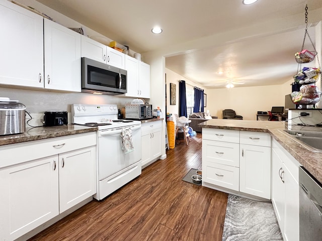 kitchen featuring white cabinets, appliances with stainless steel finishes, sink, dark hardwood / wood-style floors, and kitchen peninsula