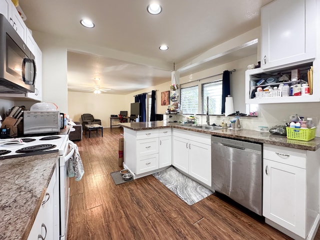 kitchen featuring dark stone countertops, stainless steel appliances, white cabinetry, and kitchen peninsula