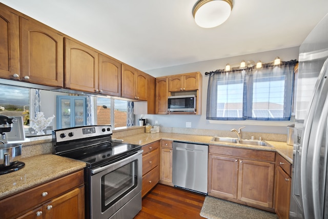 kitchen with sink, dark wood-type flooring, light stone countertops, and appliances with stainless steel finishes