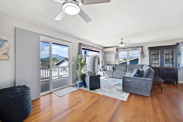 living room with hardwood / wood-style flooring, ceiling fan, and a wall mounted air conditioner