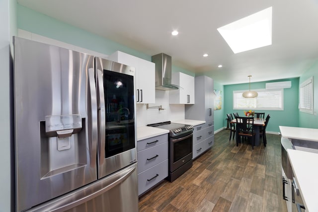 kitchen featuring white cabinetry, hanging light fixtures, stainless steel appliances, a wall unit AC, and wall chimney exhaust hood