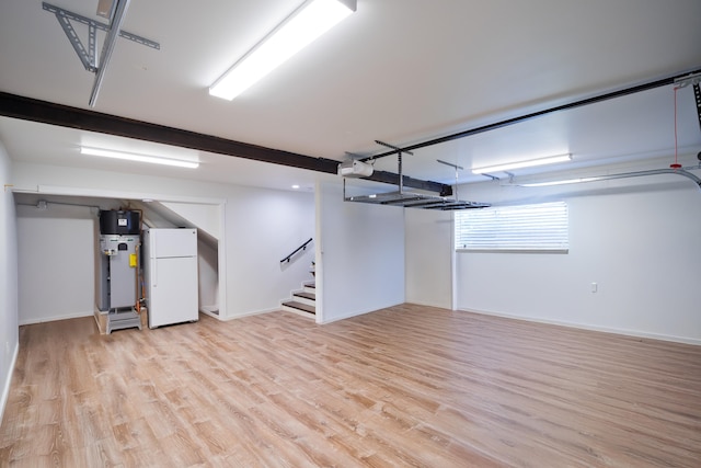 basement featuring white refrigerator, water heater, and light hardwood / wood-style flooring