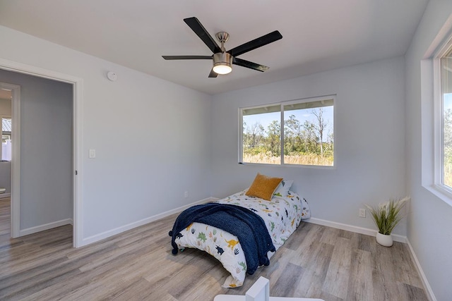 bedroom featuring multiple windows, light hardwood / wood-style flooring, and ceiling fan