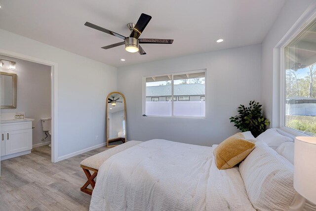 bedroom featuring connected bathroom, multiple windows, ceiling fan, and light hardwood / wood-style floors