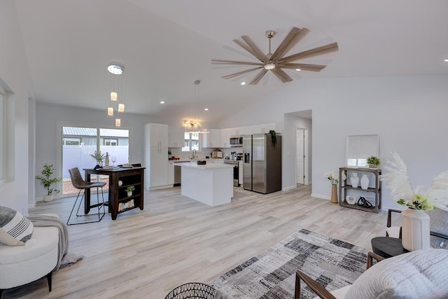 living room with ceiling fan, light hardwood / wood-style flooring, lofted ceiling, and sink