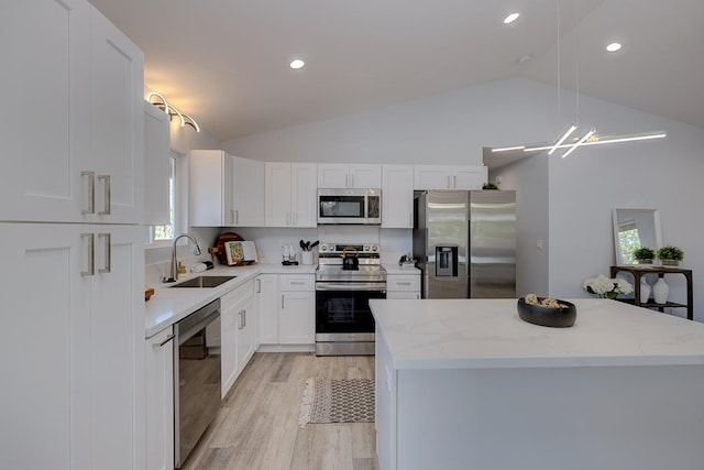 kitchen featuring sink, an inviting chandelier, lofted ceiling, white cabinets, and appliances with stainless steel finishes