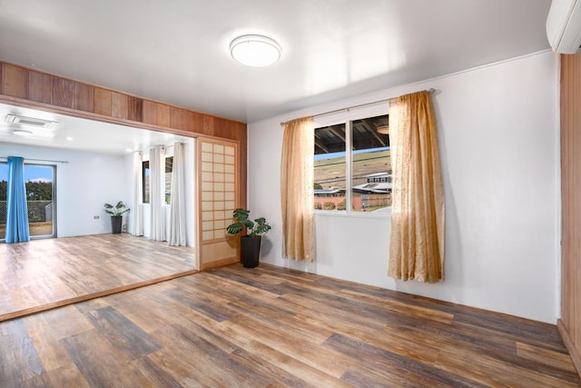 empty room featuring wood-type flooring and a wall unit AC