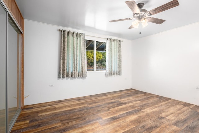 unfurnished bedroom featuring dark hardwood / wood-style flooring, ceiling fan, and a closet