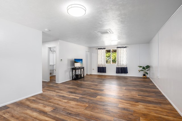 unfurnished living room featuring a textured ceiling and dark hardwood / wood-style floors