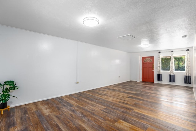 empty room with dark hardwood / wood-style flooring and a textured ceiling