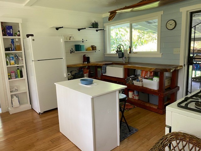 kitchen featuring wood walls, sink, white appliances, and light hardwood / wood-style floors