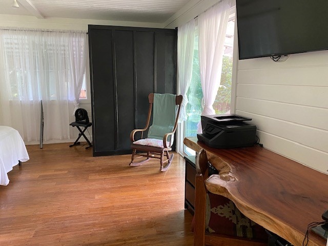 bedroom with light hardwood / wood-style floors and beamed ceiling