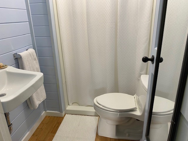 bathroom with toilet, wood-type flooring, and a shower with shower curtain