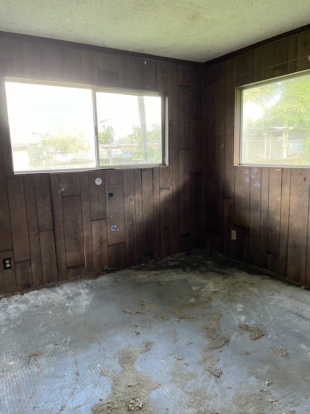 unfurnished room featuring a textured ceiling and wooden walls