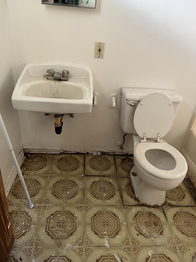 bathroom with sink, toilet, and tile patterned flooring