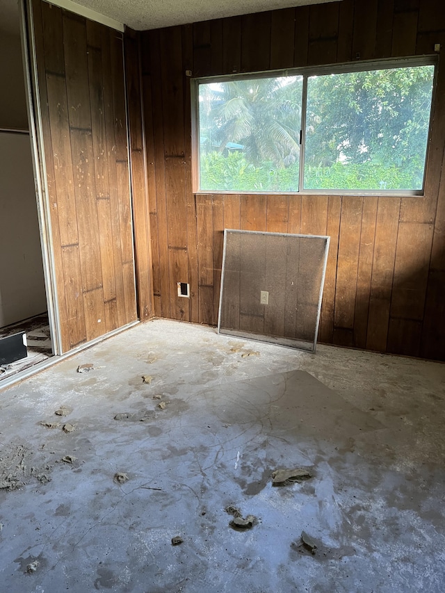 spare room featuring wood walls, concrete flooring, and a wealth of natural light