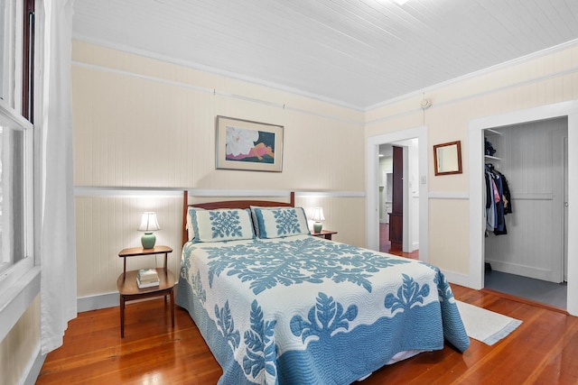 bedroom with hardwood / wood-style flooring, a walk in closet, crown molding, and a closet