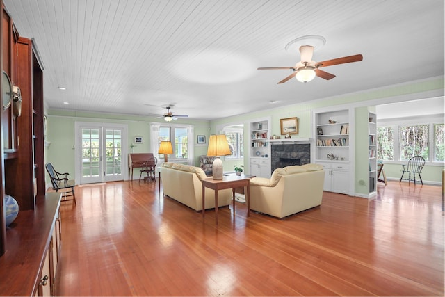 living room with a fireplace, built in shelves, light hardwood / wood-style flooring, and wood ceiling