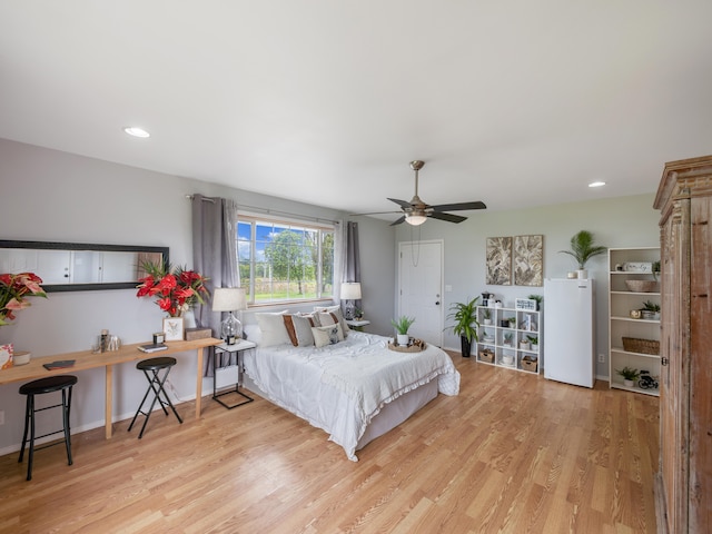 bedroom featuring white refrigerator, light hardwood / wood-style flooring, and ceiling fan