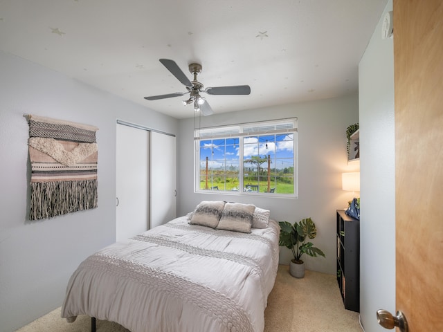 carpeted bedroom with ceiling fan and a closet