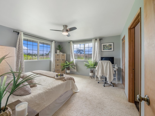 bedroom featuring multiple windows, light carpet, a closet, and ceiling fan