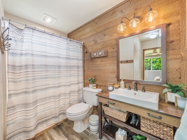 bathroom featuring hardwood / wood-style floors, vanity, wooden walls, toilet, and curtained shower