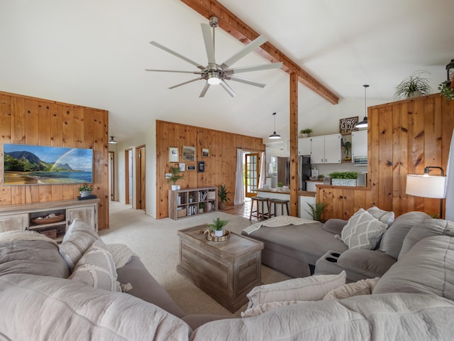 carpeted living room with beam ceiling, wood walls, ceiling fan, and high vaulted ceiling