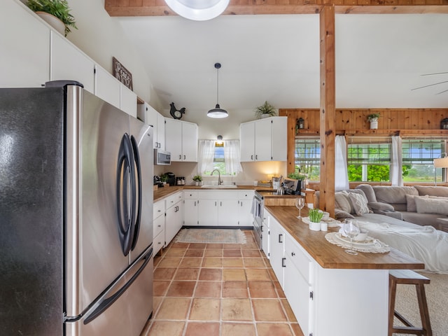 kitchen with wooden walls, white cabinets, wooden counters, and appliances with stainless steel finishes