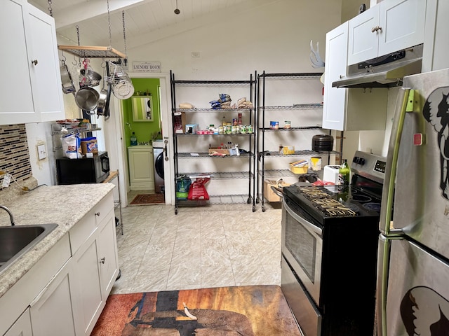 kitchen with appliances with stainless steel finishes, light stone counters, lofted ceiling with beams, washing machine and clothes dryer, and white cabinets