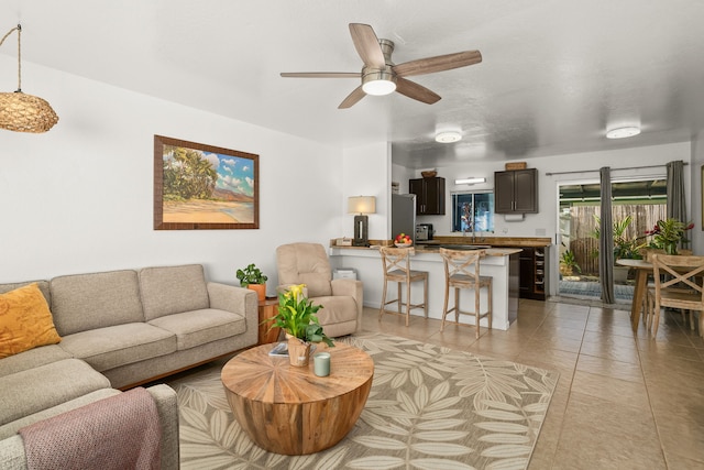 tiled living room with ceiling fan and sink