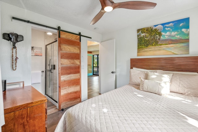 bedroom with a barn door, ceiling fan, and hardwood / wood-style floors